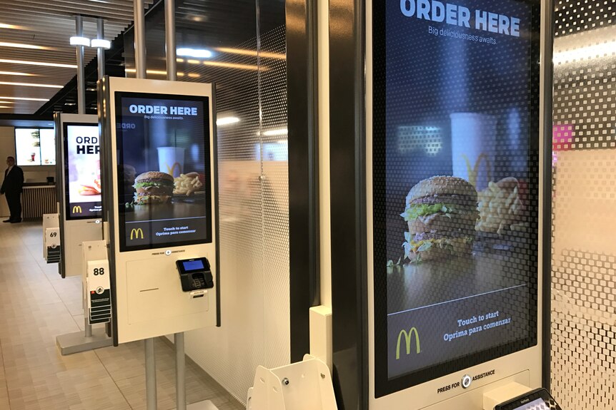A row of self-serve screens displaying McDonald's food.