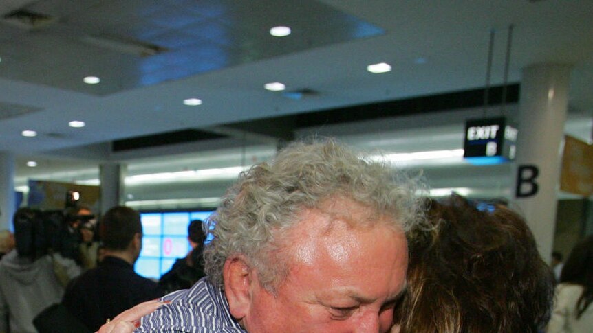 Qantas airline passenger Peter Smith embraces family members after landing at Sydney International Airport.