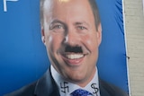 A campaign photo of Josh Frydenberg, with a Hitler-like moustache drawn on his face and a Swastika and dollar sign on his collar