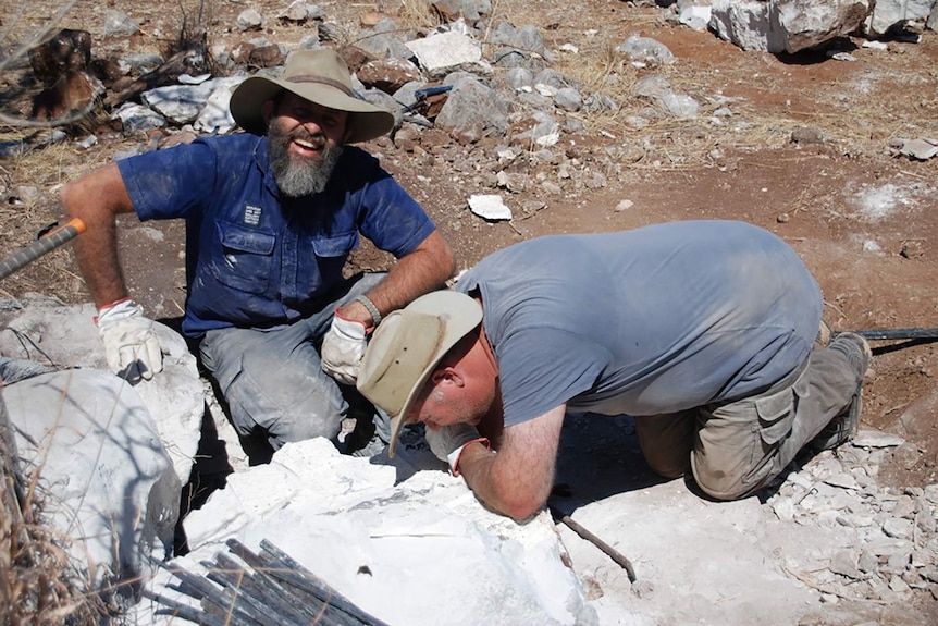 A photo of Adam inspecting some split, white limestone while Jared smiles at the camera.