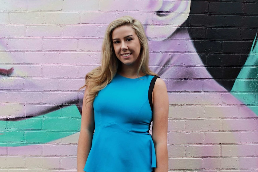 Emma Dignon stands in front of street art