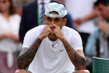 Nick Kyrgios sits on a chair with his hands to his eyes at Wimbledon.