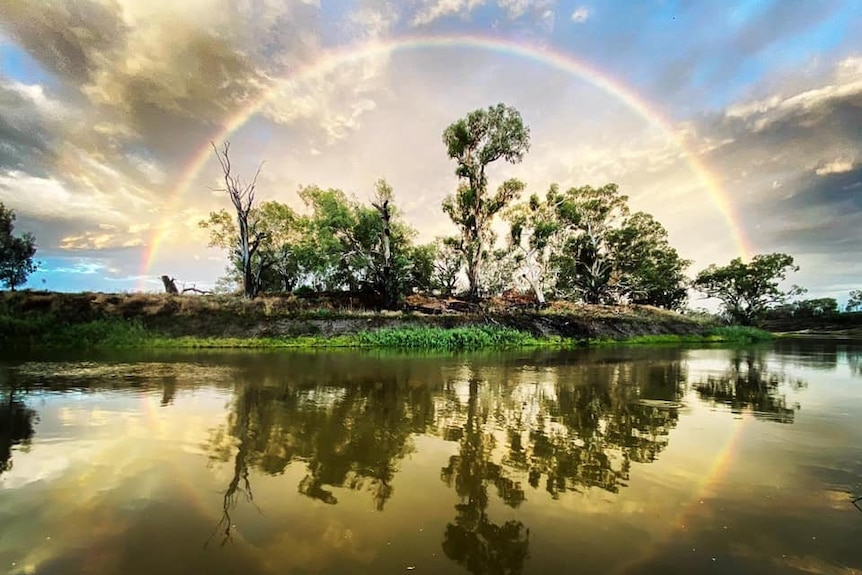 A rainbow over a river, with the reflection of the rainbow in the river making a perfect circle