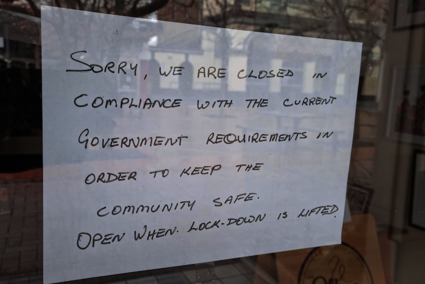 Sign on a shop window that reads: "Sorry, we are closed in compliance with the current government requirements"