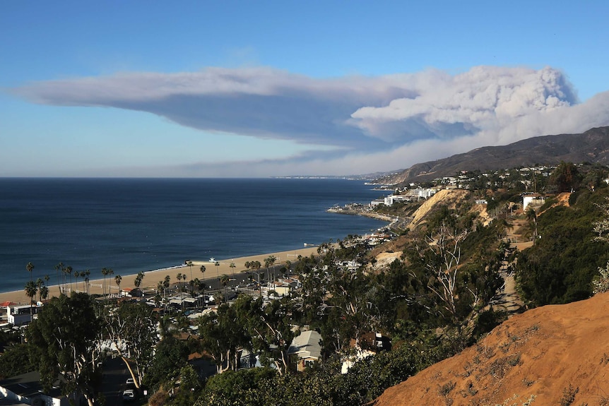 smoke blows horizontally over the the Santa Monica Mountains and the Pacific Ocean over the city of Malibu