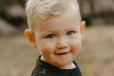 A blonde-haired Lincoln Browne smiles as he stands outdoors, dressed in a black t-shirt.