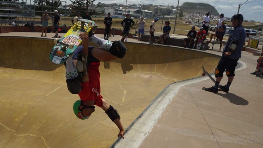 A skateboarder performs a trick upside down