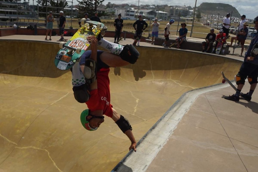 A skateboarder performs a trick upside down