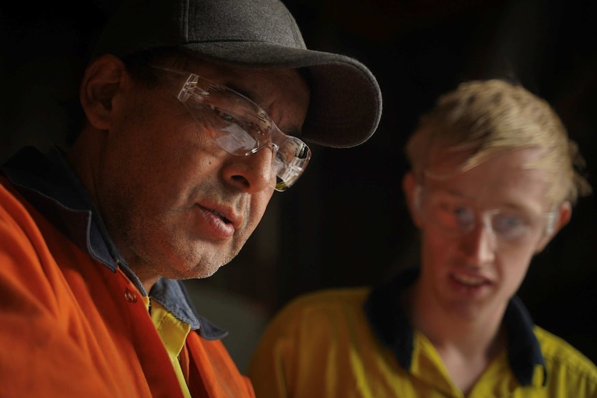 Samuel Brito and Roydon Featherstone look down at their work.