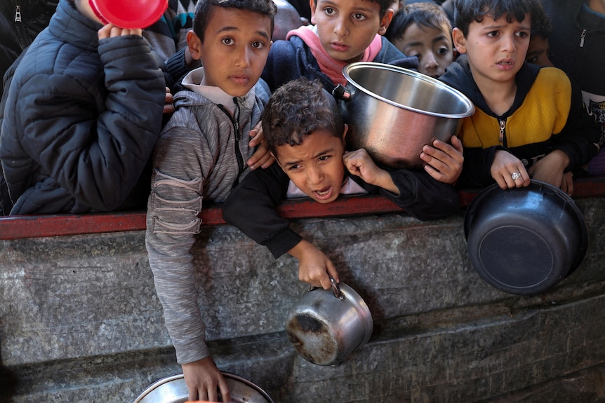 Children wait with receptacles including pots and cups.