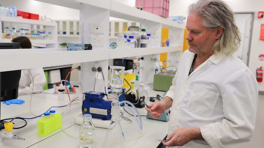 Scientist in lab looking at beaker of water