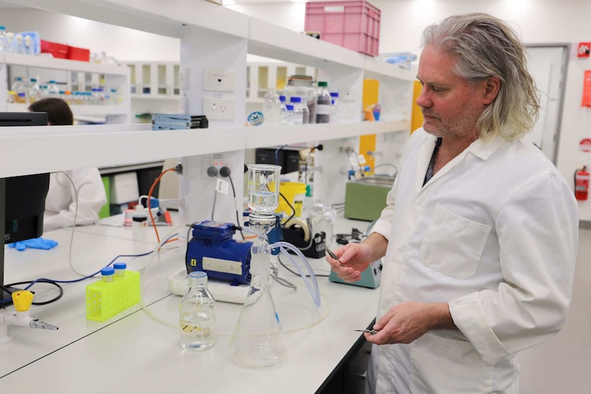 Scientist in lab looking at beaker of water