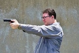 Federal MP George Christensen aims a handgun.
