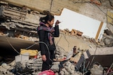 A woman cries in rubble 