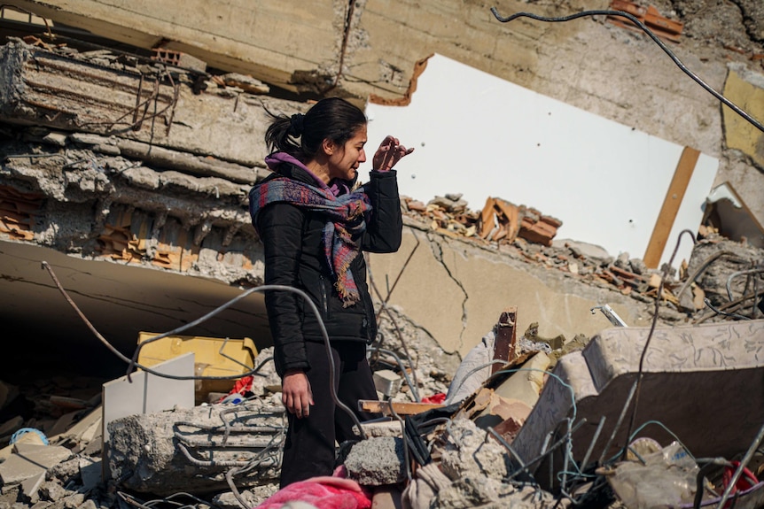 A woman cries in rubble 