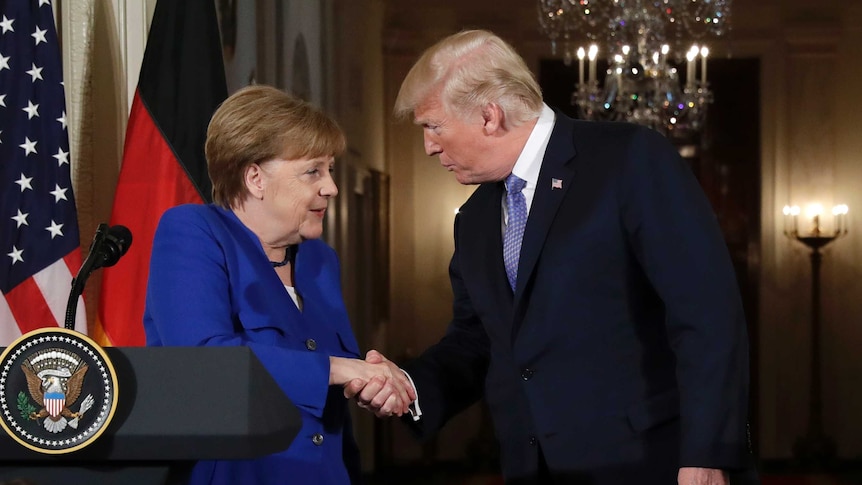Donald Trump shakes hands with Angela Merkel
