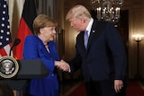 Donald Trump shakes hands with Angela Merkel