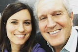 A woman and an older man smile in a selfie shot.