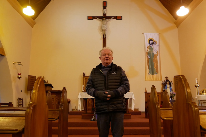 a priest stands in front of a cross inside a church