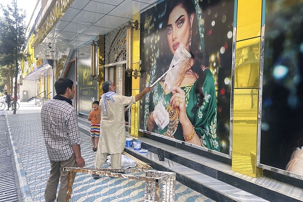 A man paints over the image of a woman in Kabul