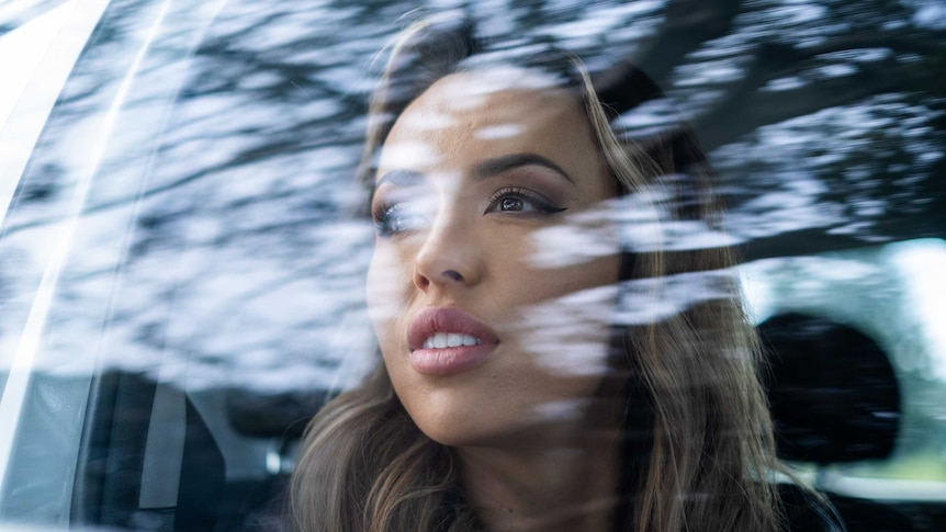 a young woman stares up at the sky through car window