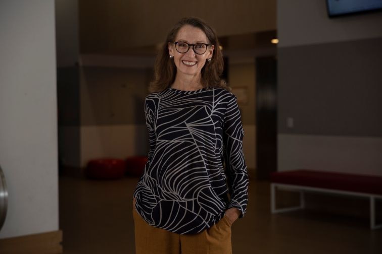 A women standing with hands in her pockets and smiling