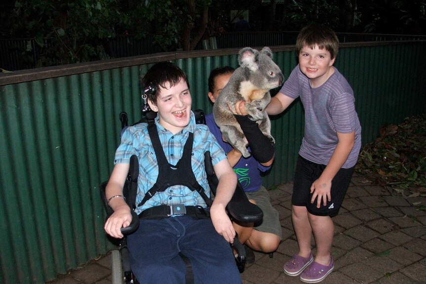 Harrison Creevey with his brother Jae, both smiling with a koala.