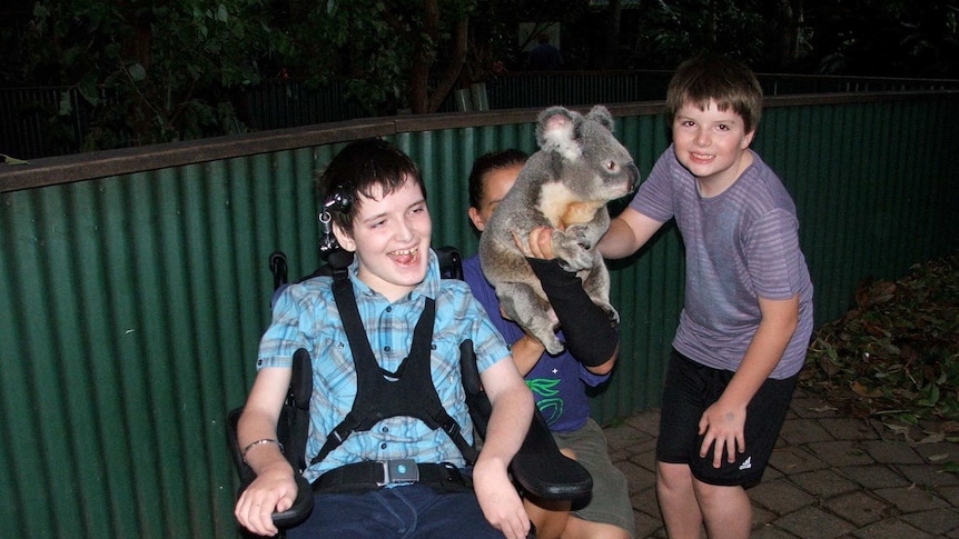 Harrison Creevey with his brother Jae, both smiling with a koala.