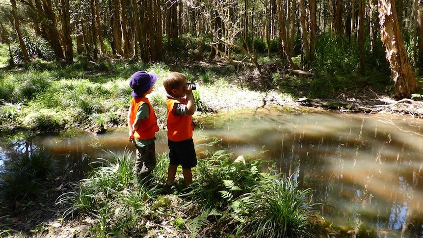 The Nature School encourages children to show independence and explore the outdoors- two boys stand by a creek