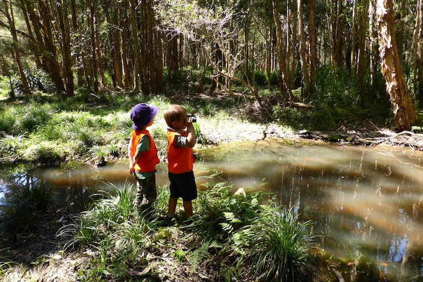 Two boys stand by a creek