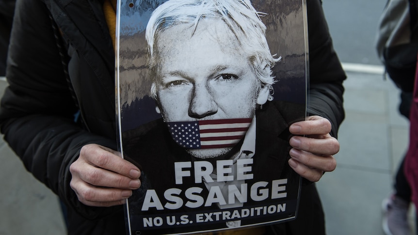 Close up of woman's hands holding poster that says, "Free Assange, no US extradition".