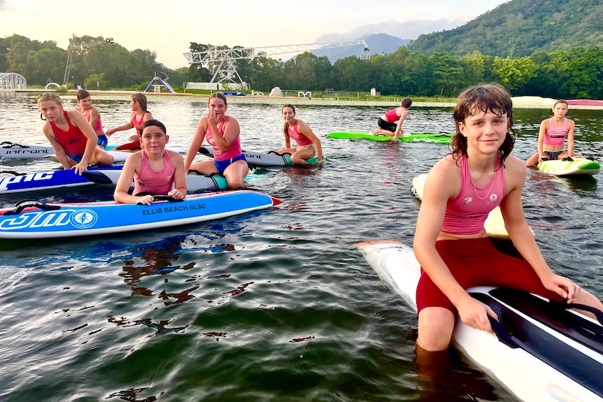  A group of children sit on paddle boards at a cable ski park in Cairns