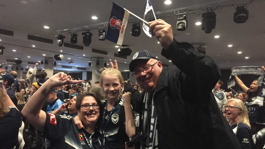 Melbourne Victory fans salute the camera.