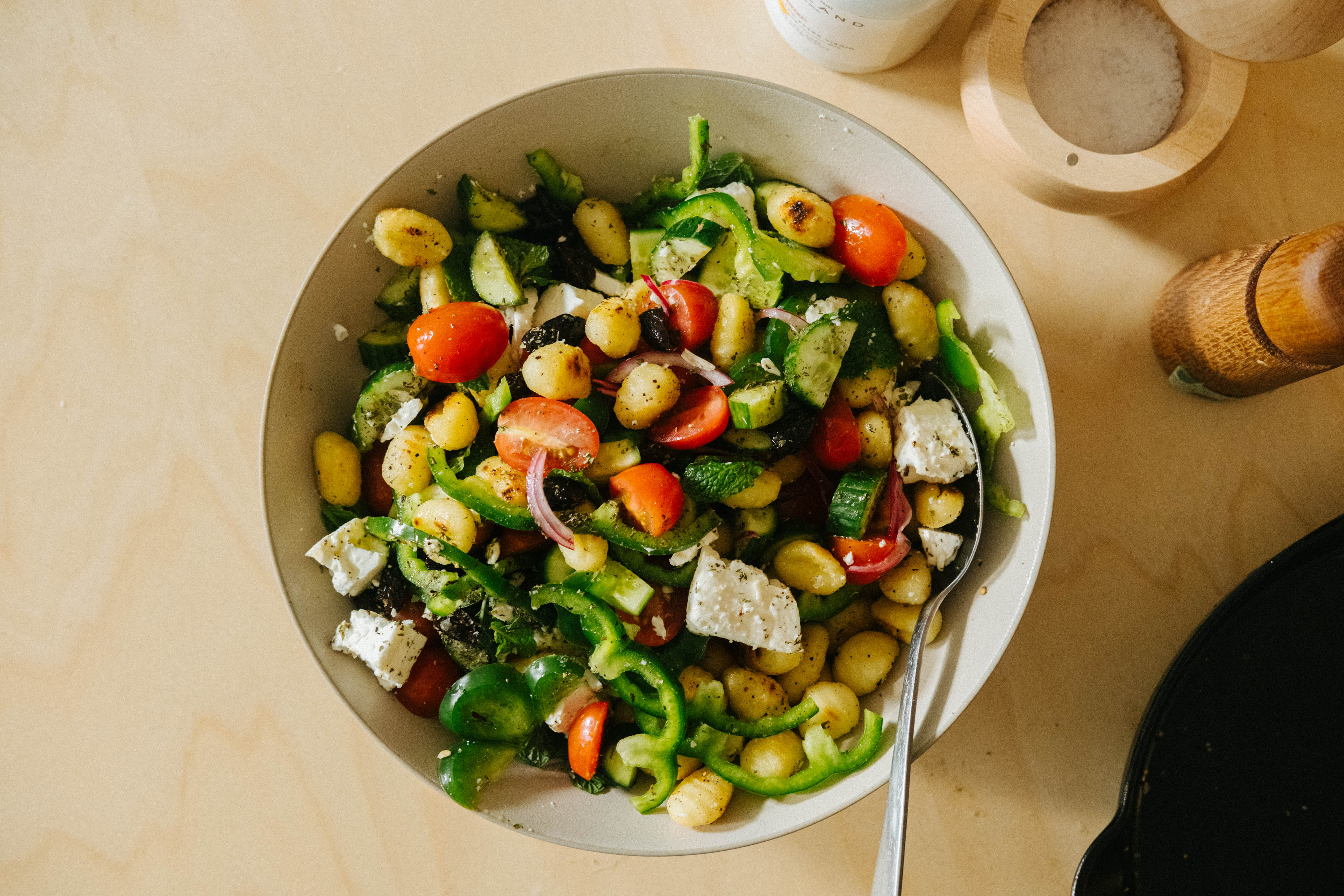 A serving bowl of Greek salad with the addition of pan-fried gnocchi, a colourful and easy dinner.