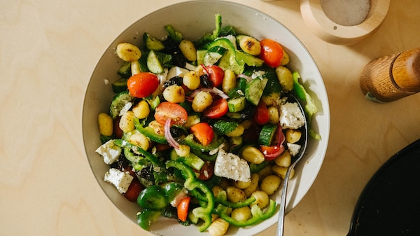 A serving bowl of Greek salad with the addition of pan-fried gnocchi, a colourful and easy dinner.