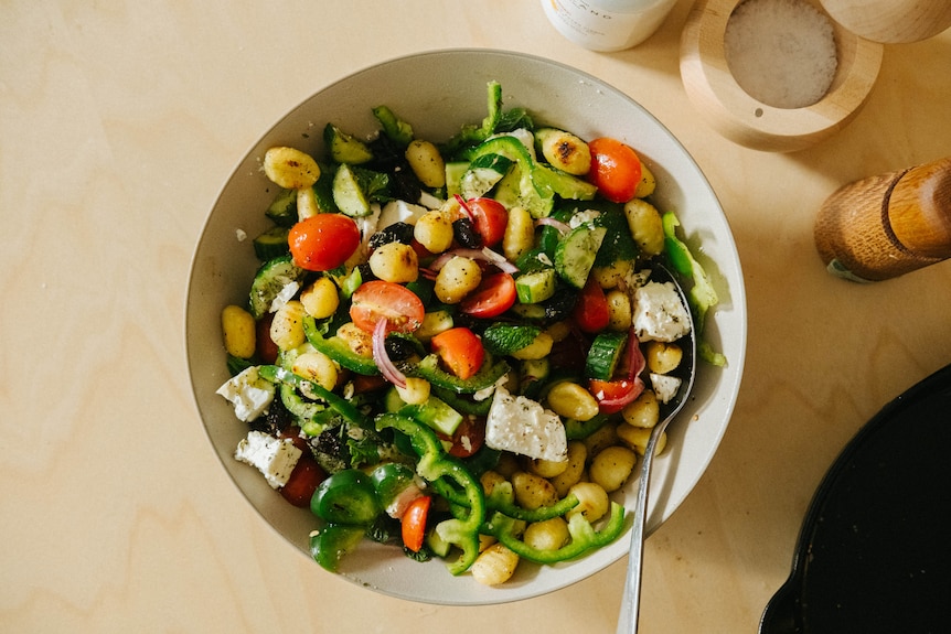 A serving bowl of Greek salad with the addition of pan-fried gnocchi, a colourful and easy dinner.