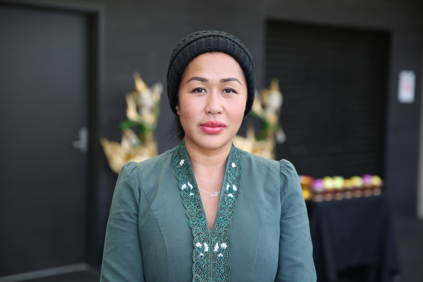 A woman in traditional northern Thai dress outside on a bright afternoon.