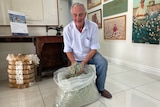 Man holds shredded cotton in his hands.