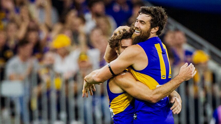 Two AFL players embrace in celebration during a match