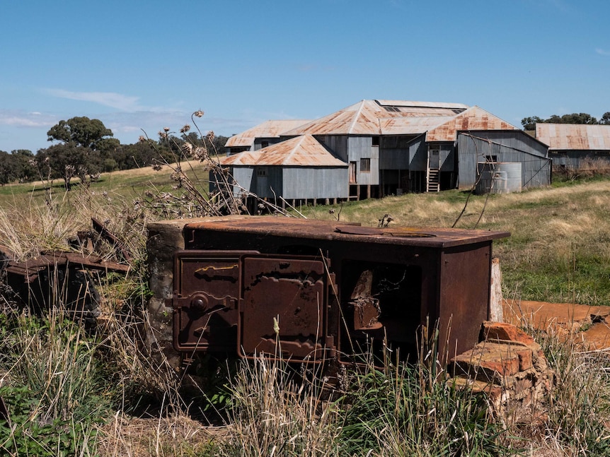 An old cast iron stove lies in ruin in front of a woolshed.