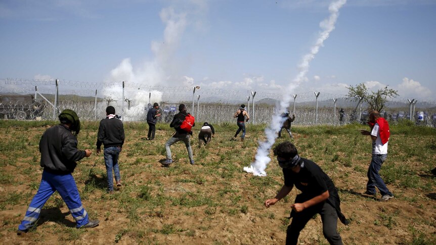 A teargas canister thrown by Macedonian police lands among protesting asylum seekers.