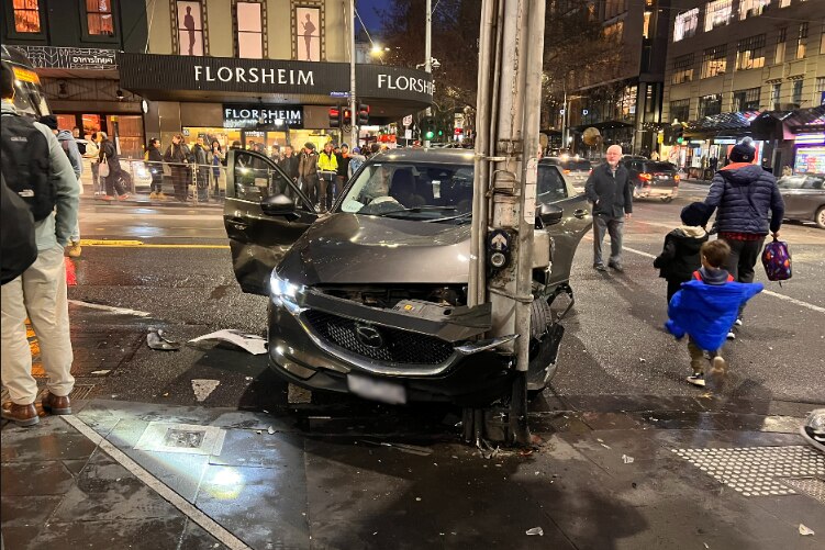 A grey Mazda vehicle crashed into a pole.