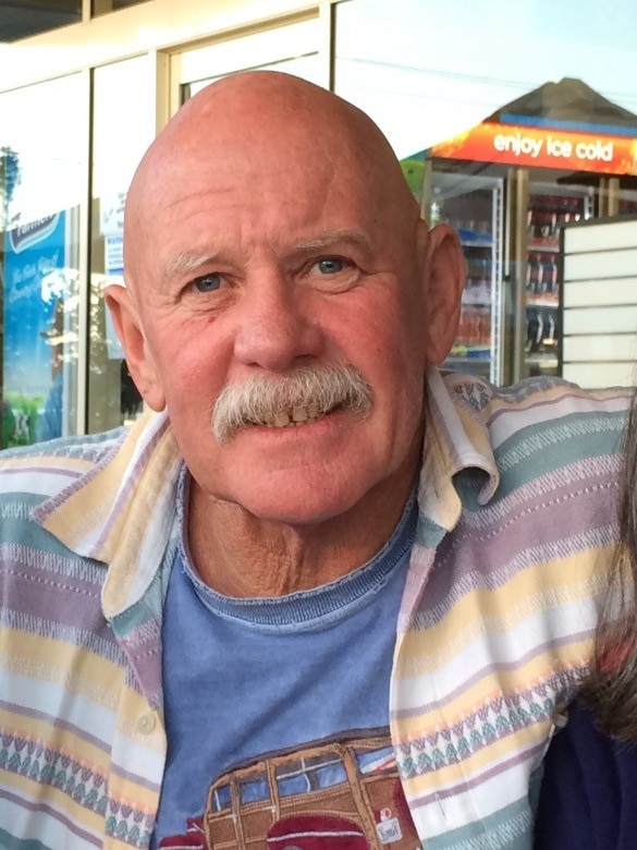 A man in a striped coloured shirt, smiling.