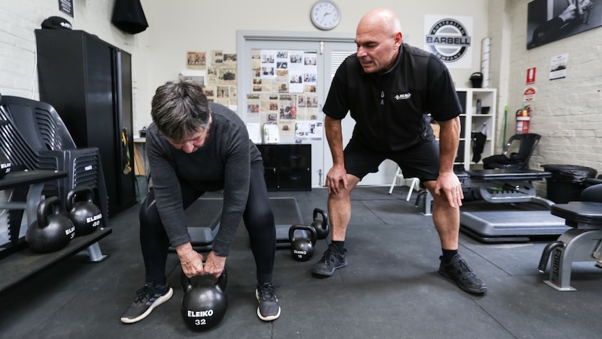 Sally Berridge lifting a Kettlebell with coach Dean Mawby beside her.