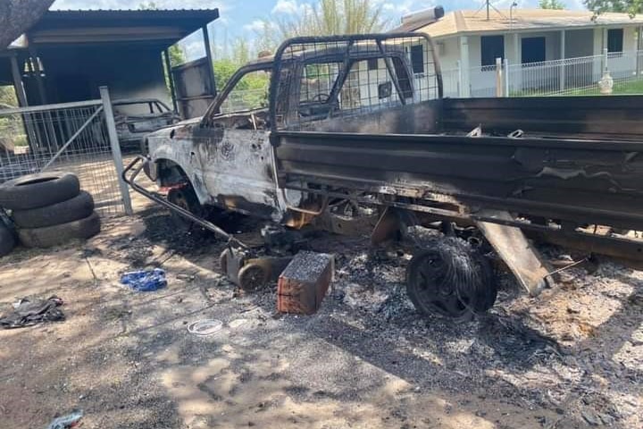 A burnt car with ashes around the wheels is seen in a driveway in the community of Daly River.