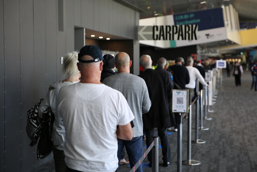 A rear view of people queued up for a COVID-19 vaccination.