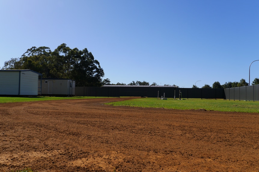 A large patch of freshly turned earth at a camping ground beneath a clear sky.