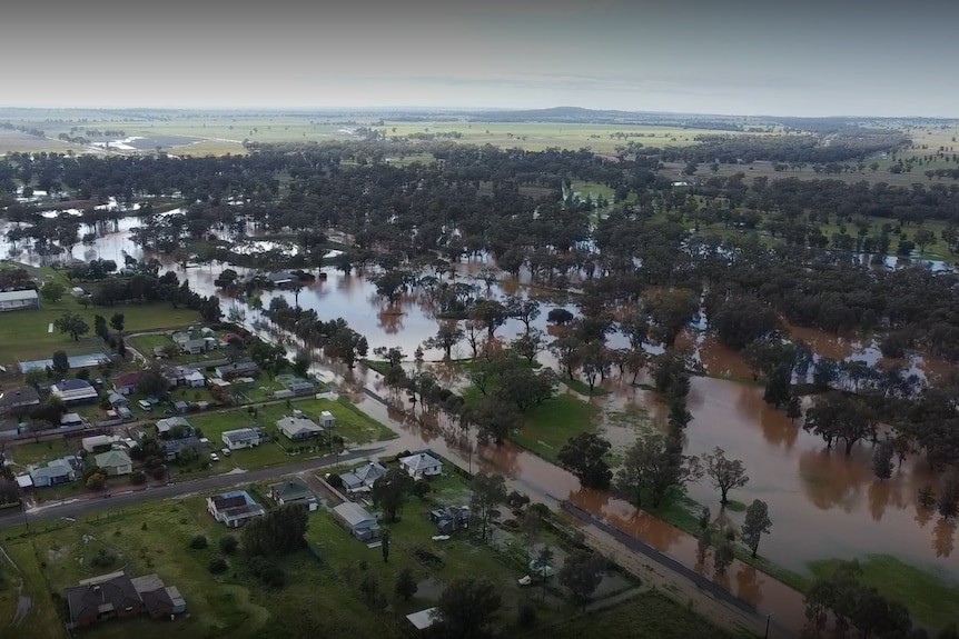 An aerial shot of a small town surrounded by brown flood water.