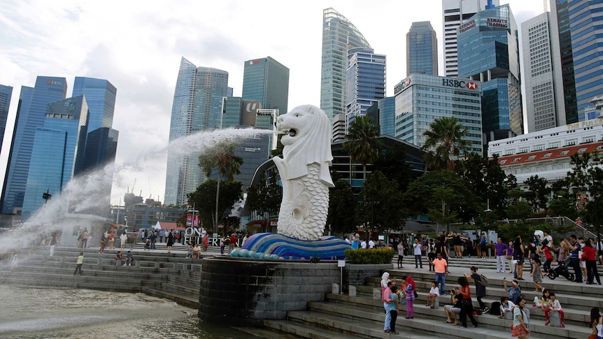 Tourists take pictures next to the Merlion statue in the central business district of Singapore
