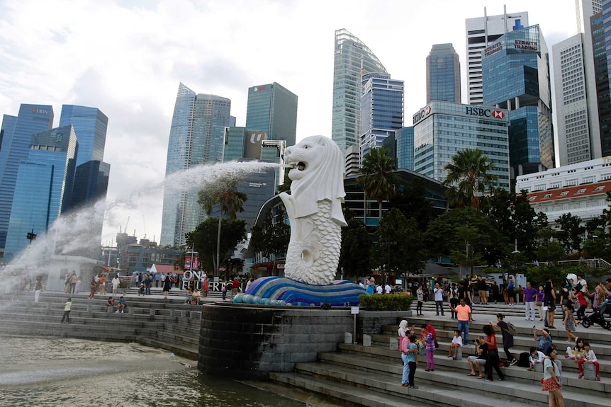 Tourists take pictures next to the Merlion statue in the central business district of Singapore